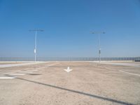 an empty parking lot with two street lights on the top of each pole on a sunny day