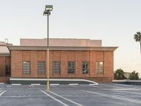 a streetlight in an empty parking lot on top of a building with brick walls