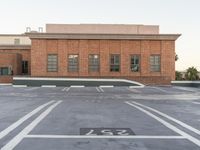 a streetlight in an empty parking lot on top of a building with brick walls