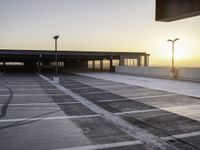 an empty parking lot at sunrise with sun reflecting off the building's windows and lighting poles