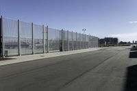 empty parking lot on a clear day with fencing and a car parked next to it