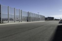 empty parking lot on a clear day with fencing and a car parked next to it