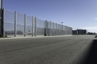 empty parking lot on a clear day with fencing and a car parked next to it