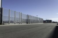 empty parking lot on a clear day with fencing and a car parked next to it