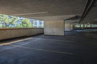 an empty parking lot with a concrete wall and trees in the background and buildings on both sides