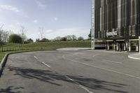 an empty parking lot is shown in the middle of a cityscape with grass, trees and skyscraper