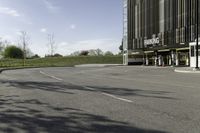 an empty parking lot is shown in the middle of a cityscape with grass, trees and skyscraper