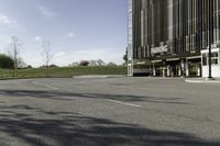 an empty parking lot is shown in the middle of a cityscape with grass, trees and skyscraper