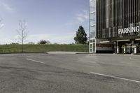 an empty parking lot is shown in the middle of a cityscape with grass, trees and skyscraper