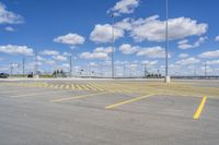 an empty parking lot with yellow markings on the ground beneath clouds in blue skys