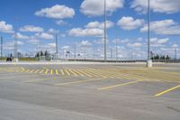 an empty parking lot with yellow markings on the ground beneath clouds in blue skys