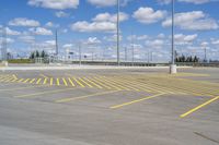 an empty parking lot with yellow markings on the ground beneath clouds in blue skys