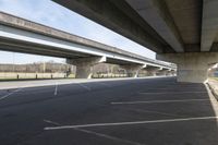 a wide empty lot under an overpass under the freeway bridge near other vehicles on the highway