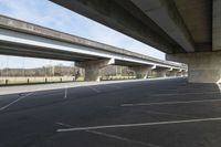 a wide empty lot under an overpass under the freeway bridge near other vehicles on the highway