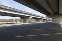 a wide empty lot under an overpass under the freeway bridge near other vehicles on the highway