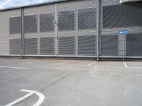 an empty parking lot near a building with several windows on it and a blue traffic sign