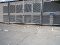 an empty parking lot near a building with several windows on it and a blue traffic sign