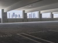 a empty parking lot with skyscraper in the distance, and a few car spaces inside of it