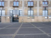 an empty parking lot next to some brick building with many windows and balconies