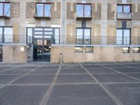 an empty parking lot next to some brick building with many windows and balconies