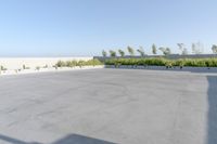 an empty parking lot in front of a building next to a field of grass and bushes