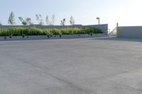 an empty parking lot in front of a building next to a field of grass and bushes