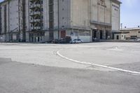 an empty parking lot with a truck parked next to it and a building in the background