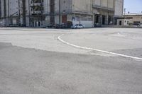 an empty parking lot with a truck parked next to it and a building in the background