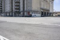 an empty parking lot with a truck parked next to it and a building in the background