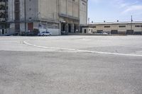 an empty parking lot with a truck parked next to it and a building in the background