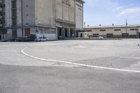 an empty parking lot with a truck parked next to it and a building in the background