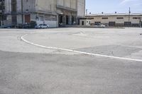 an empty parking lot with a truck parked next to it and a building in the background