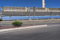 an empty parking lot with some water behind it and signs on the side of it