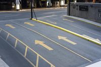 an empty parking lot with yellow arrows painted on the street side of it's curb