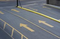 an empty parking lot with yellow arrows painted on the street side of it's curb