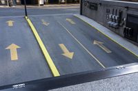 an empty parking lot with yellow arrows painted on the street side of it's curb