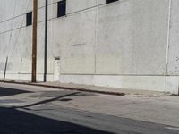 the parking meter is empty near the side of the building on the sidewalk beside the street