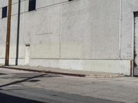 the parking meter is empty near the side of the building on the sidewalk beside the street