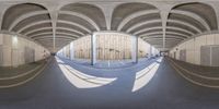 a fish - eye view of an empty parking space with columns and curved concrete ceilinging