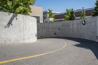 an empty parking space with yellow lines and no cars on it in the background, and building with concrete walls