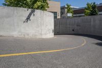 an empty parking space with yellow lines and no cars on it in the background, and building with concrete walls