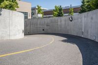 an empty parking space with yellow lines and no cars on it in the background, and building with concrete walls
