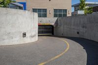 an empty parking space with yellow lines and no cars on it in the background, and building with concrete walls