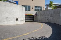 an empty parking space with yellow lines and no cars on it in the background, and building with concrete walls