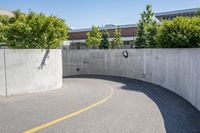 an empty parking space with yellow lines and no cars on it in the background, and building with concrete walls