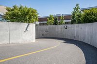 an empty parking space with yellow lines and no cars on it in the background, and building with concrete walls