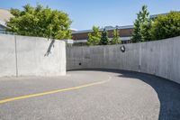 an empty parking space with yellow lines and no cars on it in the background, and building with concrete walls