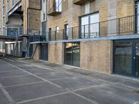 an empty parking space in front of a brick building with stairs and balconies