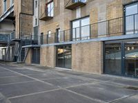 an empty parking space in front of a brick building with stairs and balconies