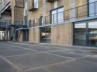 an empty parking space in front of a brick building with stairs and balconies